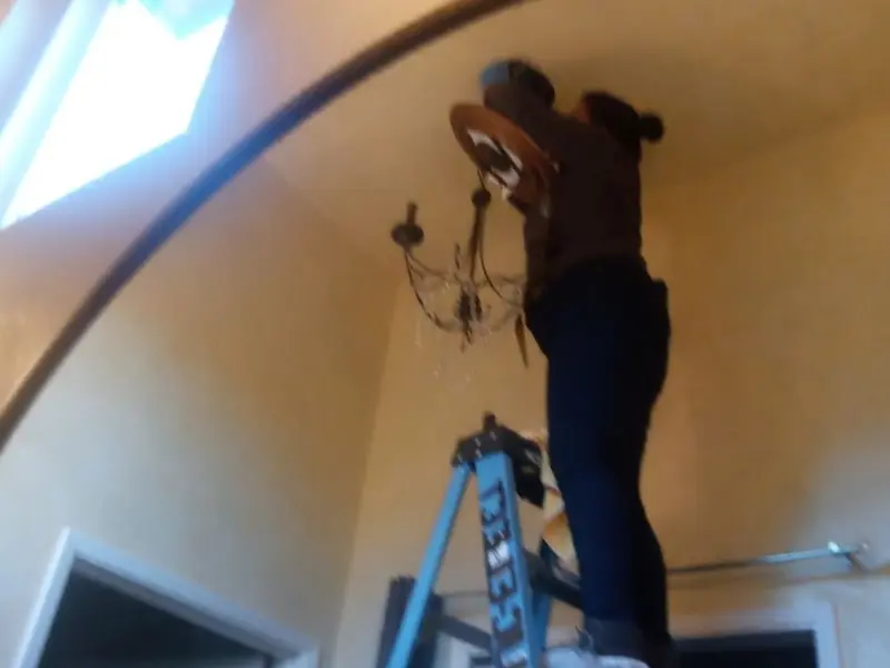 Electrician installing a chandelier in a Brownsville residence